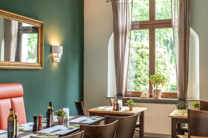 Blick im La Taverna: Fenster, einfallendes Licht, Tische und grün gestrichene Wand