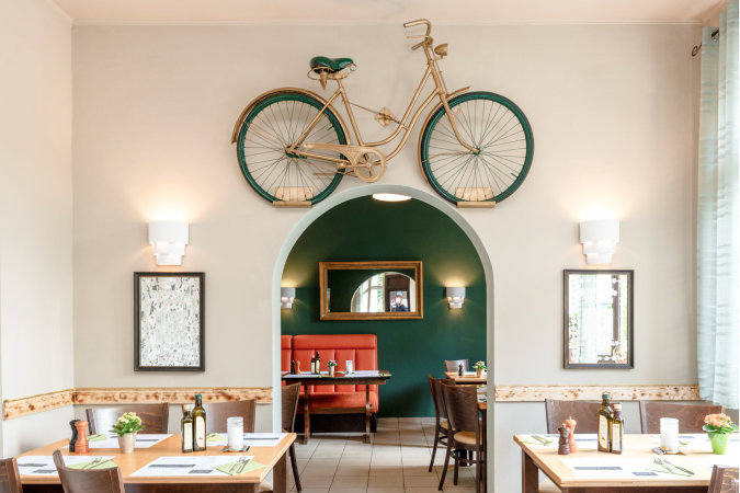 Fahrrad über Türbogen: Einblick in ein italienisches Restaurant mit freundlicher Atmosphäre